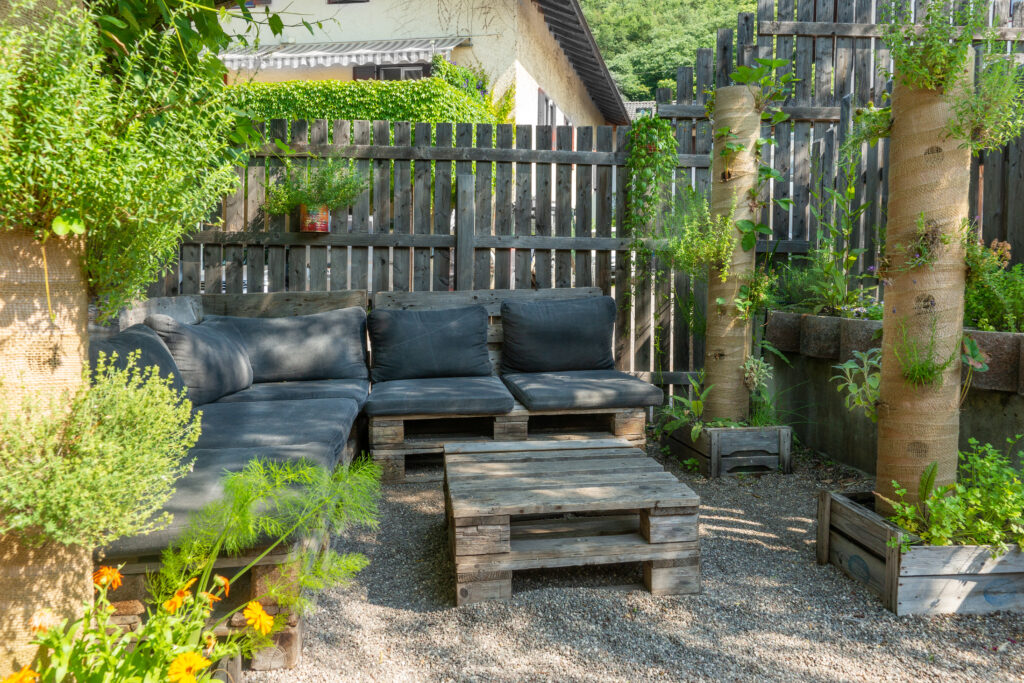 Hemgjorda möbler och skuggtåliga växter i en trädgårdssittplats.